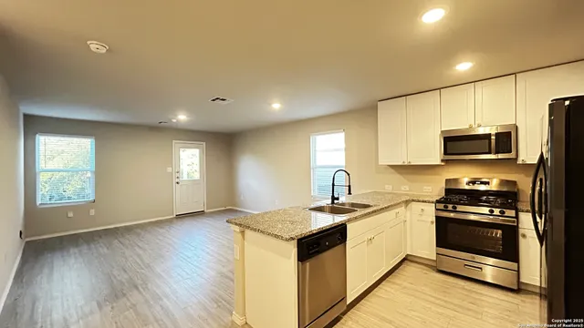 a kitchen with granite countertop a sink appliances cabinets and wooden floor
