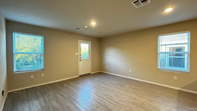 a view of an empty room with wooden floor and a window