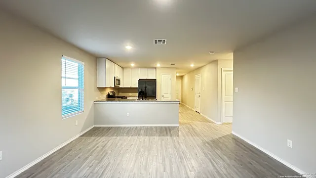 a view of kitchen with stainless steel appliances wooden floor and large window