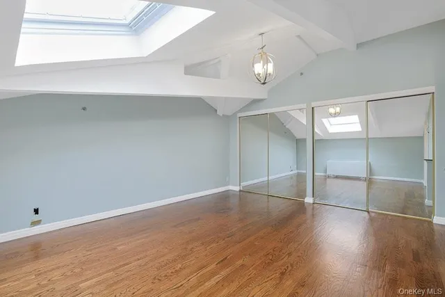 an empty room with wooden floor chandelier and windows
