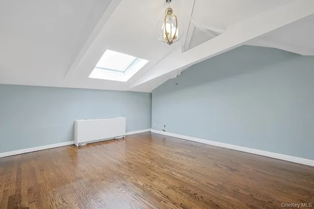 an empty room with wooden floor and chandelier