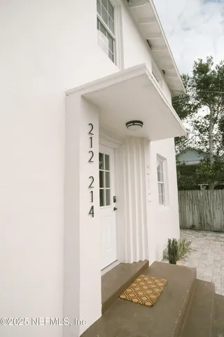 a view of a porch with a white door and wooden floor