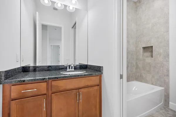 a bathroom with a granite countertop sink and a bathtub