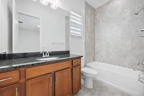 a bathroom with a granite countertop sink a toilet and bathtub