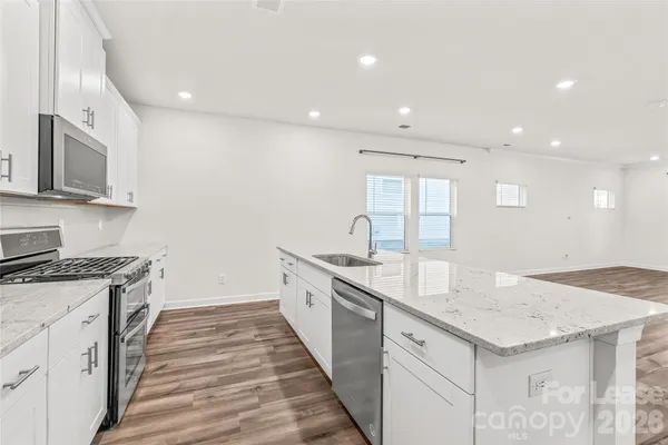 a kitchen with granite countertop kitchen island wooden floor center island and stainless steel appliances