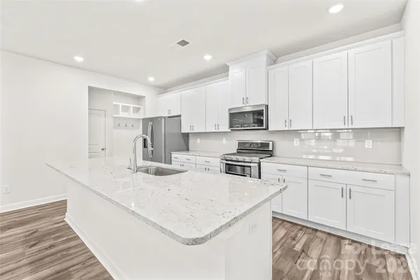 a kitchen with stainless steel appliances granite countertop a sink a stove and a refrigerator