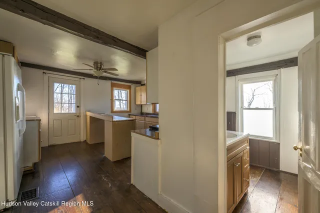 a view of a hallway with wooden floor and a living room