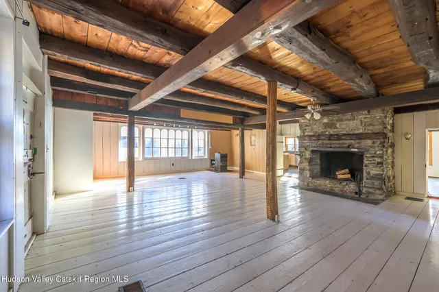 a view of an empty room with wooden floor fireplace and a window