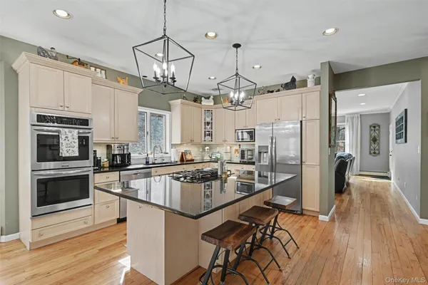 a kitchen with stainless steel appliances granite countertop a refrigerator a stove top oven a sink dishwasher and white cabinets with wooden floor