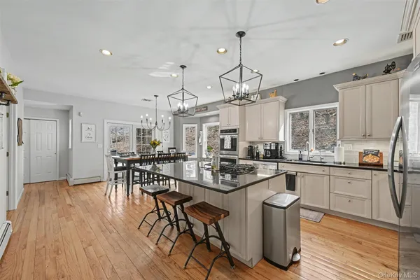 a kitchen with stainless steel appliances granite countertop a stove a refrigerator a kitchen island a dining table and chairs with wooden floor