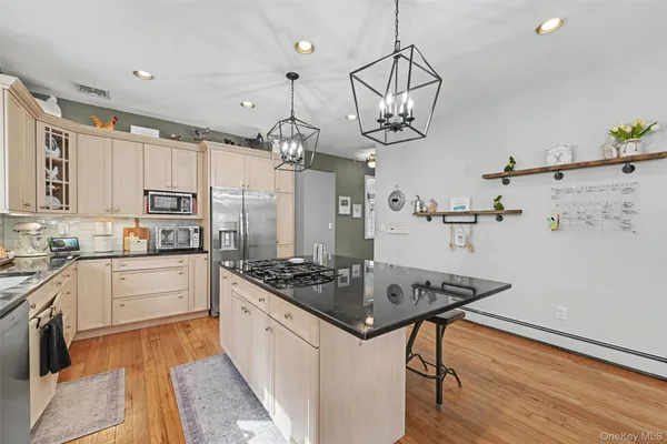 a kitchen with stainless steel appliances granite countertop a stove a sink dishwasher and a refrigerator with wooden floor