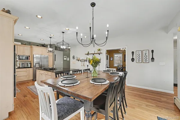 a view of a dining room and livingroom with furniture wooden floor a rug a chandelier