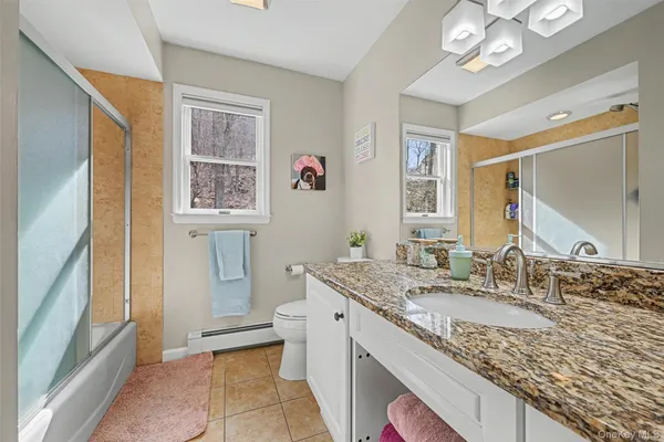 a bathroom with a granite countertop double vanity sink a mirror and a shower