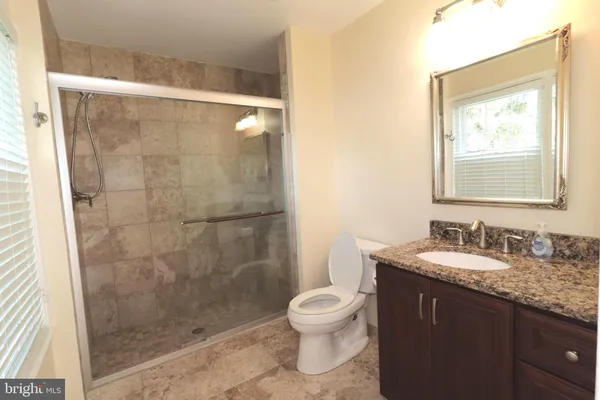 a bathroom with a granite countertop sink toilet and shower