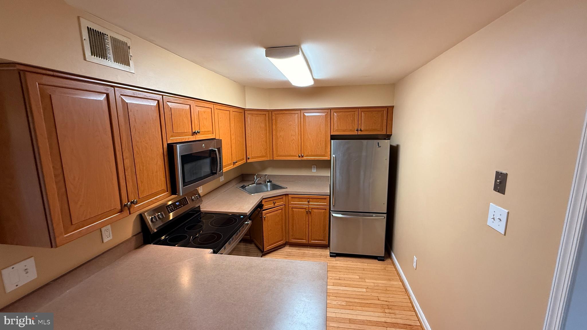 7907 Gambrill Court Springfield, VA 22153 - Photo 24 of 35 a kitchen with refrigerator a microwave and cabinets