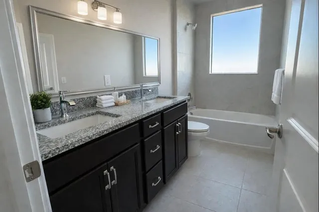 a bathroom with a granite countertop sink a toilet a mirror and shower
