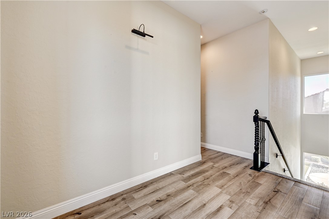 2793 Rosenhearty Drive Henderson, NV 89044 - Photo 53 of 85 A well-appointed hallway with rich wood-look flooring and a classic black banister leads to a bright stairway.