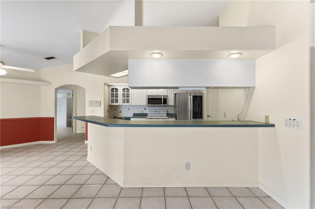 24060 Pyramid Way Punta Gorda, FL 33955 - Photo 14 of 48 Kitchen with light tile patterned floors, appliances with stainless steel finishes, ceiling fan, white cabinetry, and kitchen peninsula