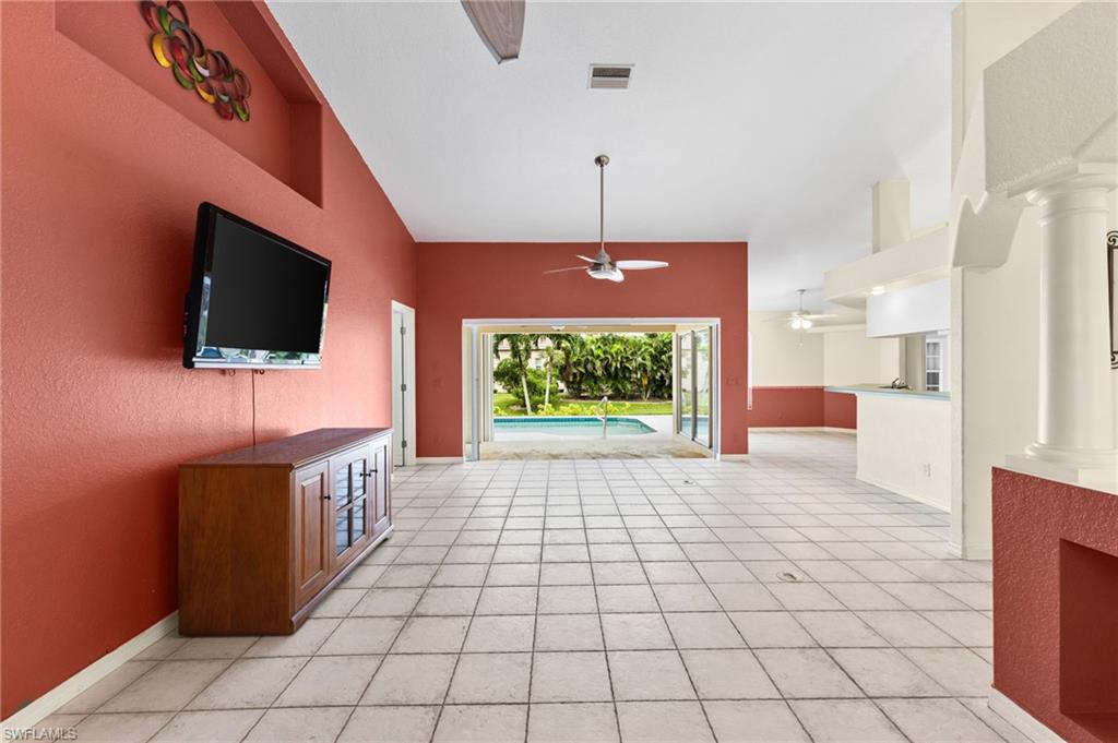 24060 Pyramid Way Punta Gorda, FL 33955 - Photo 9 of 48 Unfurnished living room featuring ceiling fan, light tile patterned flooring, high vaulted ceiling, and ornate columns