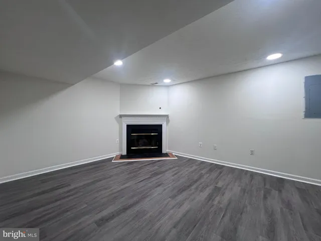 an empty room with wooden floor fireplace and windows