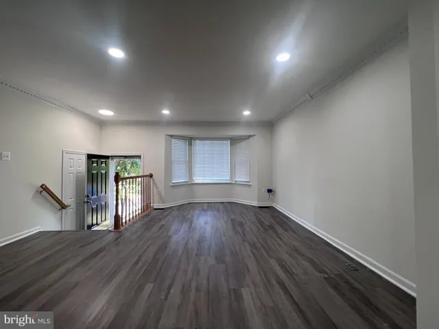a kitchen with granite countertop a refrigerator stove top oven and wooden floor