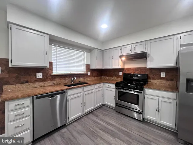 a kitchen with granite countertop a refrigerator and a sink