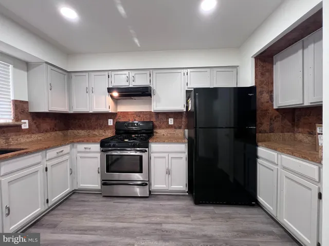 a view of an empty room with wooden floor and stairs
