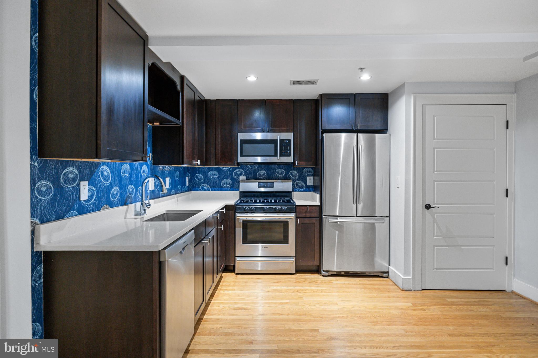 1109 M Street Northwest, Unit 1 Washington, DC 20005 - Photo 3 of 32 a kitchen with kitchen island granite countertop a stove and a refrigerator