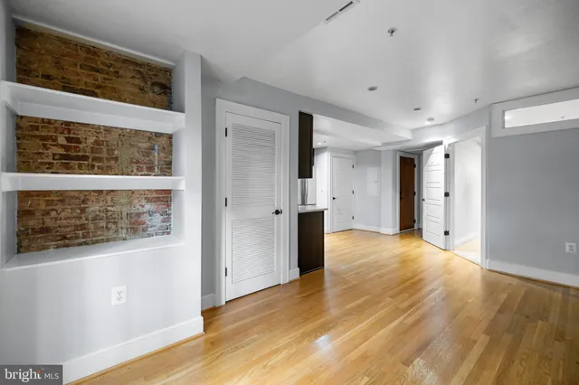 a view of an empty room with wooden floor and a window