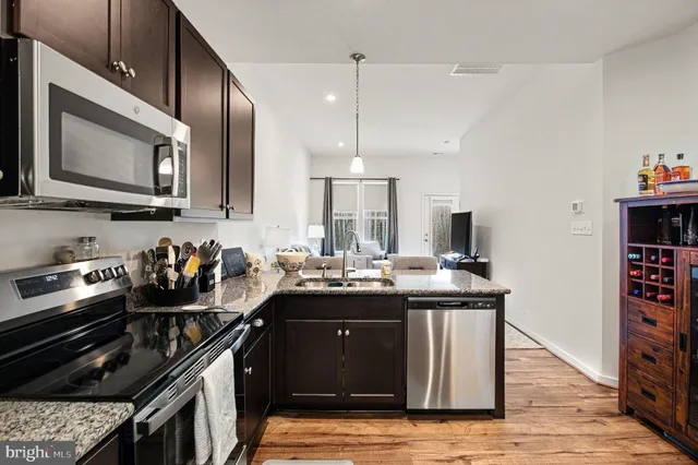 a kitchen with stainless steel appliances granite countertop a stove a sink dishwasher and a microwave oven with wooden cabinets