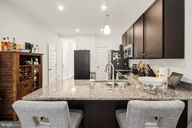 a kitchen with granite countertop kitchen island stainless steel appliances a sink and a refrigerator
