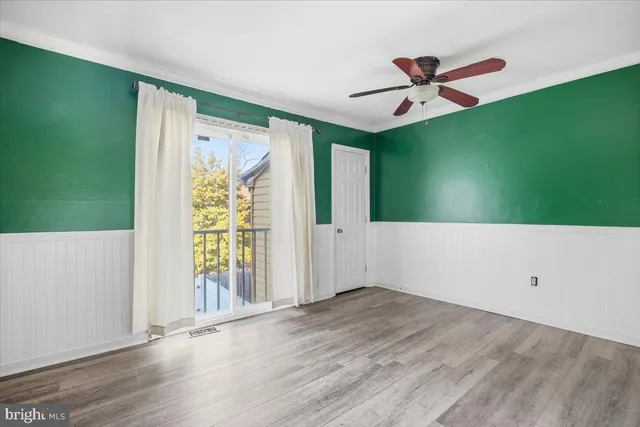 a view of a livingroom with wooden floor a ceiling fan and windows