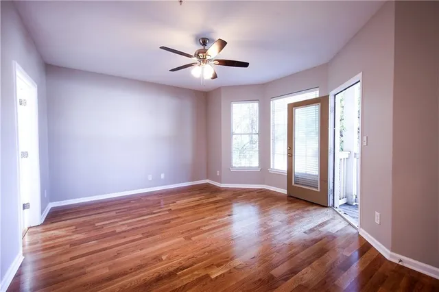 an empty room with wooden floor fan and windows