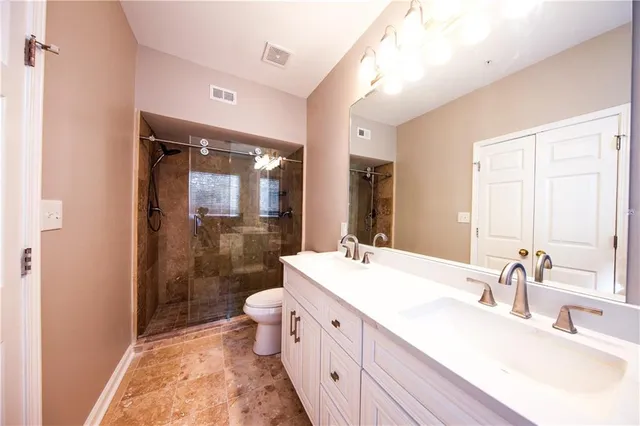 a bathroom with a double vanity sink toilet mirror and shower