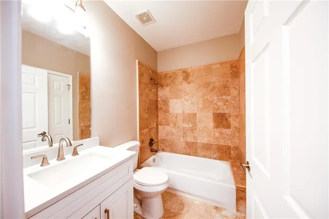 a bathroom with a bathtub shower sink vanity mirror and toilet