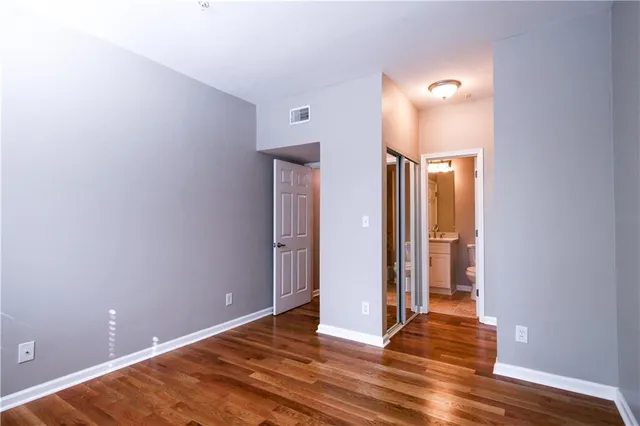 a view of an empty room with wooden floor and a bathroom