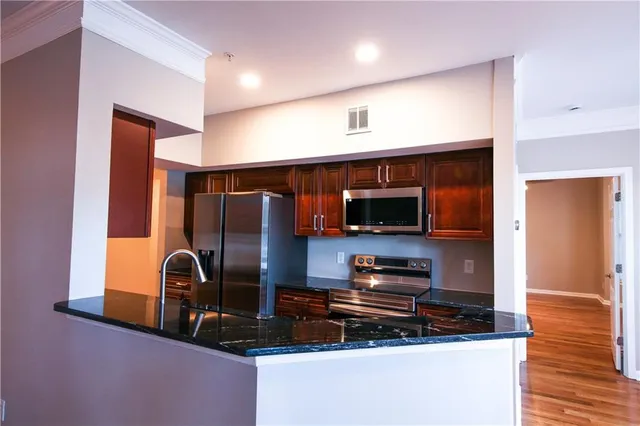 a kitchen with stainless steel appliances kitchen island granite countertop a stove and a sink