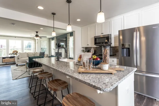 a kitchen with stainless steel appliances granite countertop a refrigerator a stove and a wooden floors