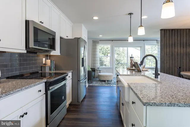 a kitchen with granite countertop a sink appliances cabinets and a counter top space