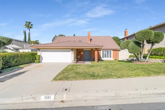 a front view of a house with a yard and potted plants