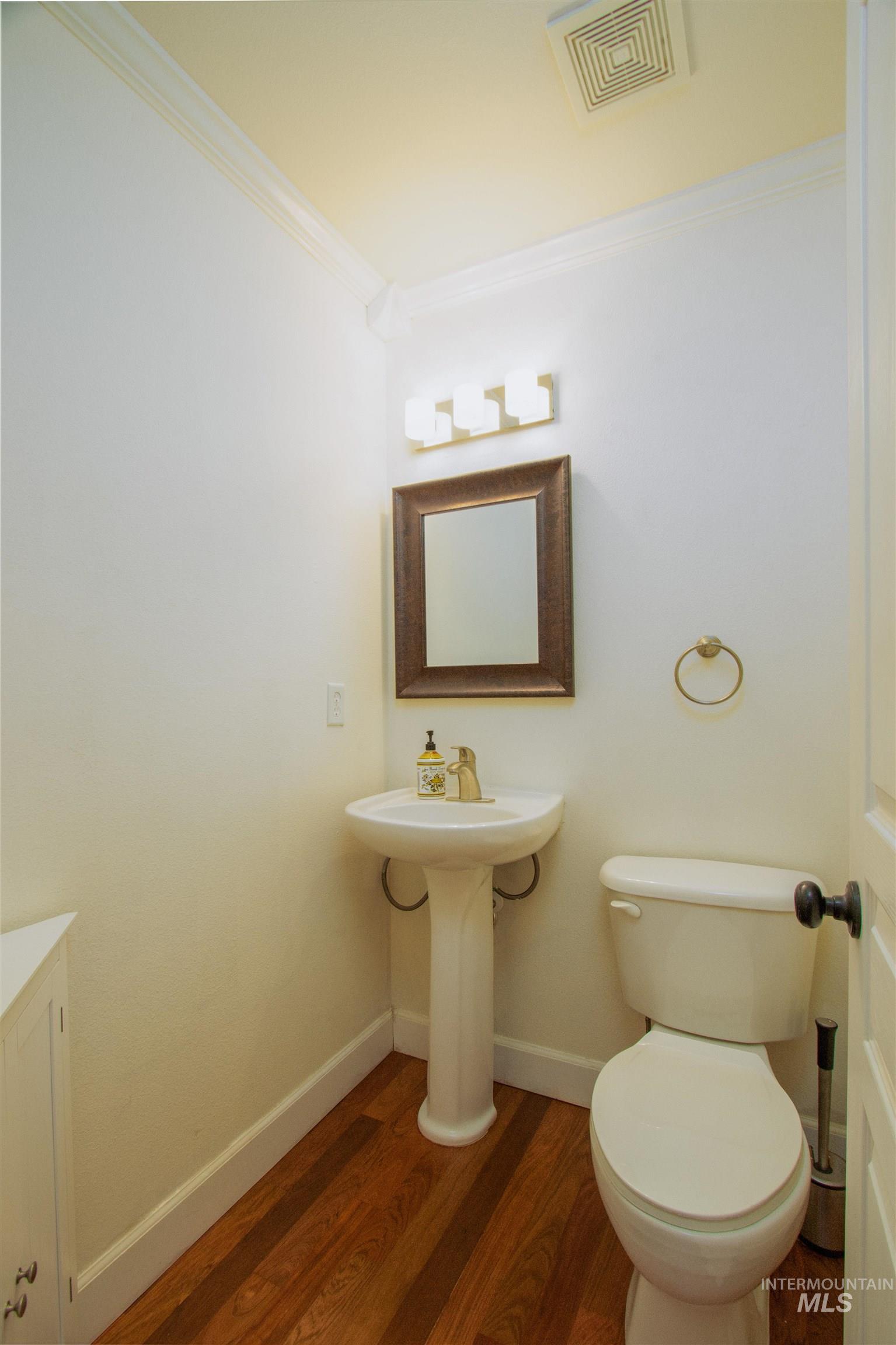 892 South Capitola Way Boise, ID 83712 - Photo 11 of 34 Pedestal sink with gold-tone faucet, white toilet, and wood-finish flooring