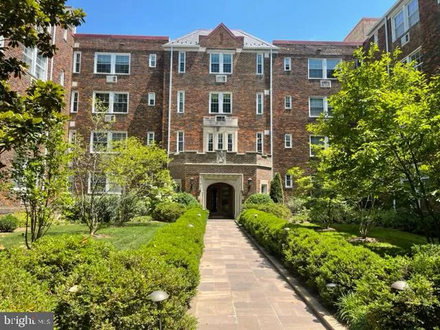 a front view of a house with garden and trees