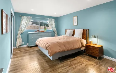 a spacious bedroom with a bed and wooden floor