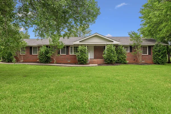 a front view of a house with a yard and trees
