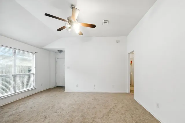 an empty room with a ceiling fan and window