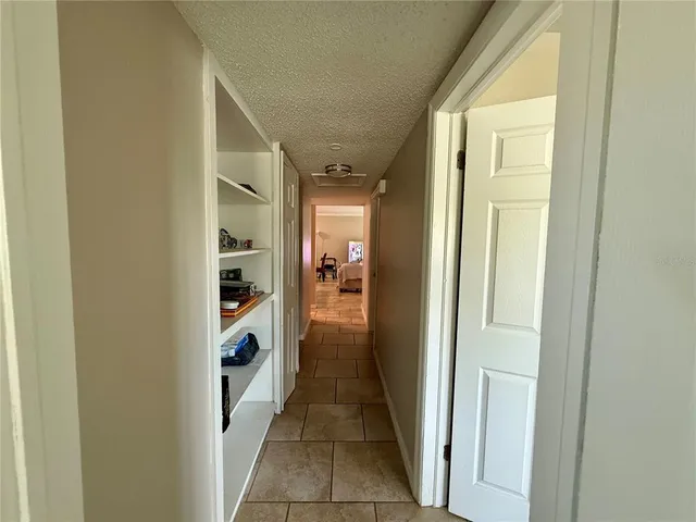 a view of a hallway with wooden floor and a bathroom