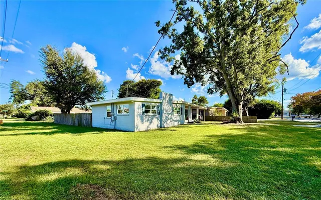 a view of a house with a big yard and large trees