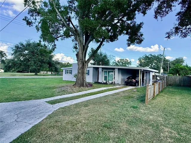 a view of a yard in front of a house with large trees