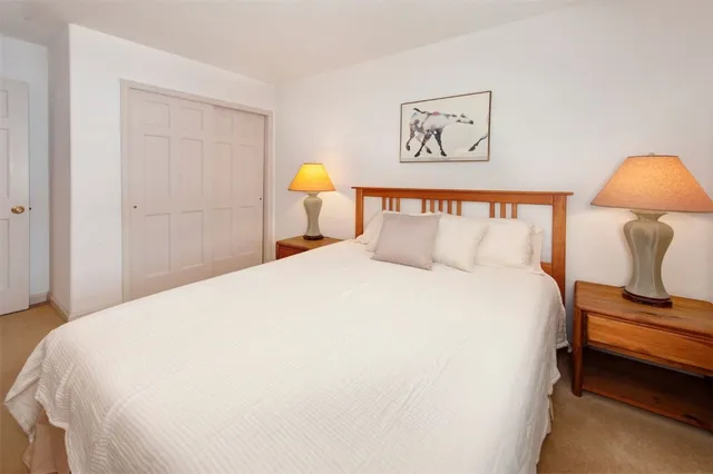 a bedroom with a bed and a lamp on dresser