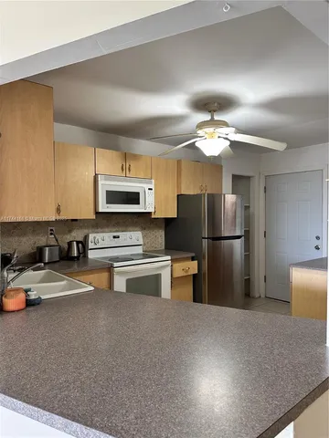 a kitchen with stainless steel appliances granite countertop a refrigerator a stove and a sink with wooden floor